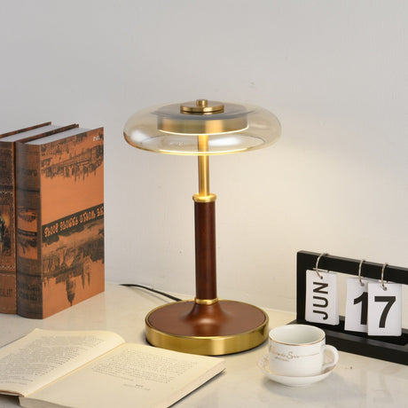 Glass disc lamp unlit on a desk beside an open book and a calendar