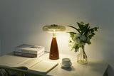 Clear glass table lamp lit on a sideboard in a dim room