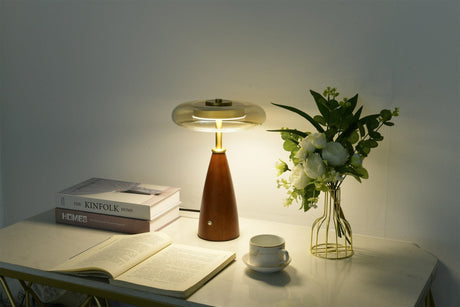 Clear glass table lamp lit on a sideboard in a dim room