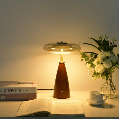 Clear glass table lamp lit close, the gold cap seen through the glass