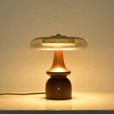 Clear glass table lamp lit against a dark ground, the glass glowing