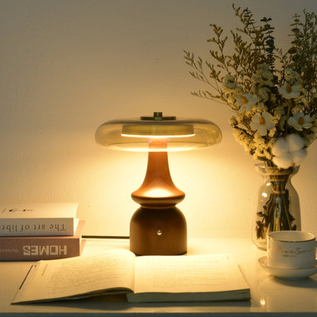 Clear glass table lamp lit warm over an open book at dusk