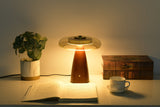 Clear glass table lamp lit in neutral white beside books