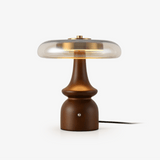 Clear glass table lamp with a gold cap on a sculpted walnut base