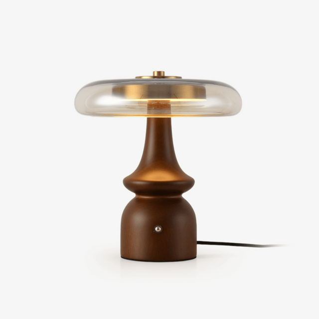 Clear glass table lamp with a gold cap on a sculpted walnut base
