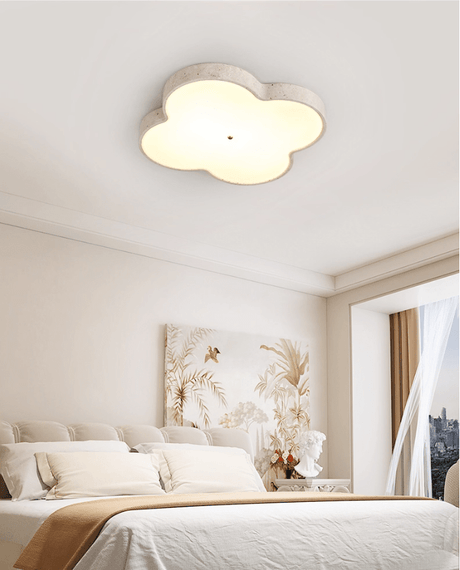 Travertine cloud ceiling lamp lit above a bed with dried grasses and sheer curtains