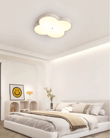 Cloud ceiling lamp lit in a bedroom with a framed print and a rounded headboard