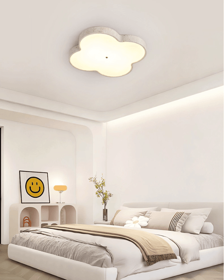 Cloud ceiling lamp lit in a bedroom with a framed print and a rounded headboard
