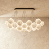 A raft of alabaster globes lit below a black canopy bar on thin cables