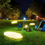Two lit on a lawn beside folding chairs and a tall garden tree