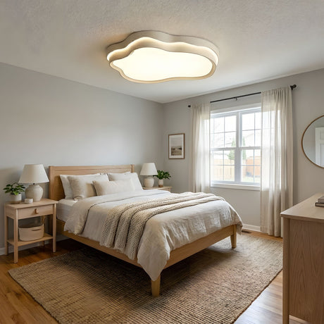 Cloud outline ceiling light above a made bed with cushions in a bedroom finished in warm neutrals