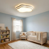 Cloud shaped ceiling fixture lit in a child's bedroom with a low bed and toys on a shelf