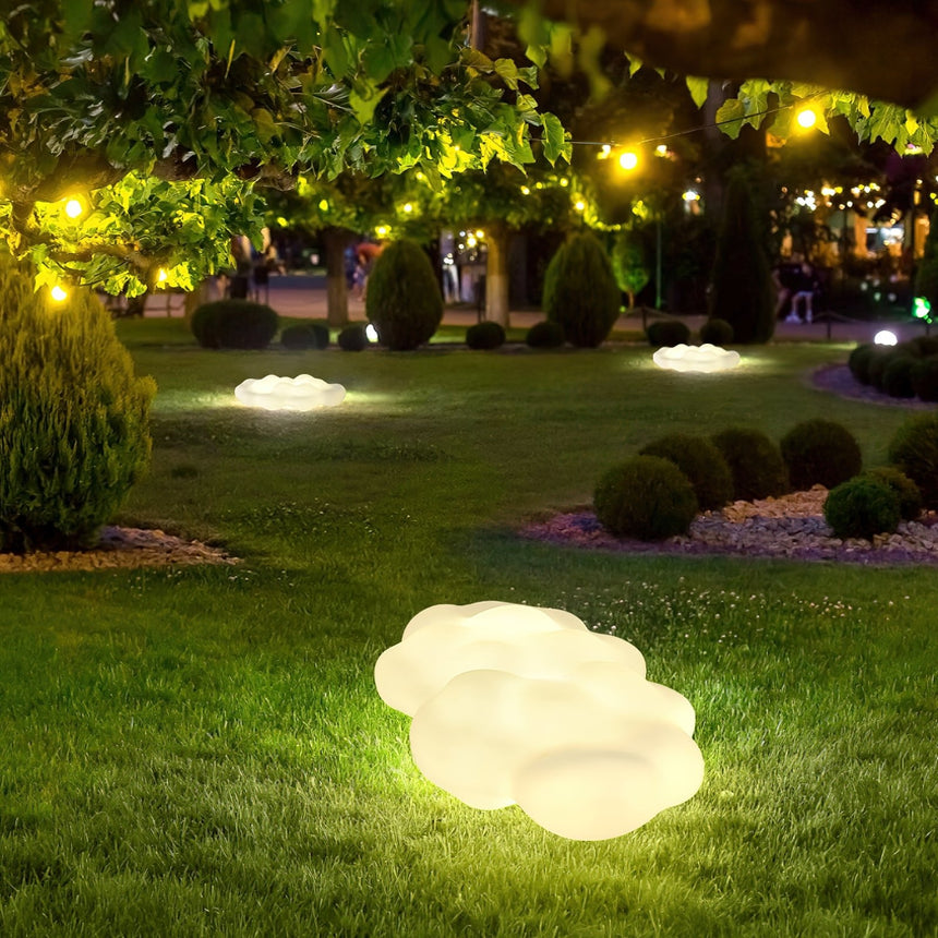 Two lit across a lawn with lit trees and low planting behind them