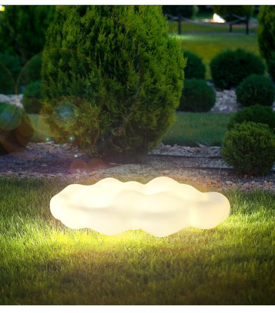 The cloud lit on a lawn beside clipped shrubs in a dark garden