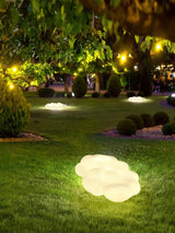 The cloud lit on a lawn under trees with a lit house behind it