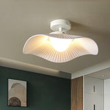 Fabric wing ceiling light lit above a room with a deep green wall and framed art