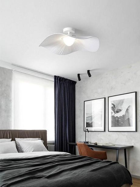 Fabric wing ceiling light above a bed with dark bedding, framed prints and a tall window