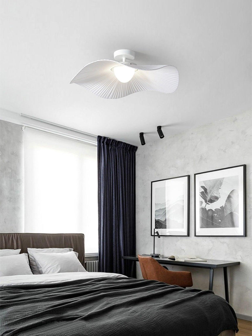 Fabric wing ceiling light above a bed with dark bedding, framed prints and a tall window