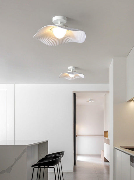 White fabric ceiling fixture lit over a kitchen with bar stools and an open doorway