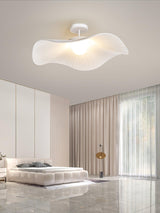 Ceiling light with fabric wings above a round bed, beige curtains and a tiled floor