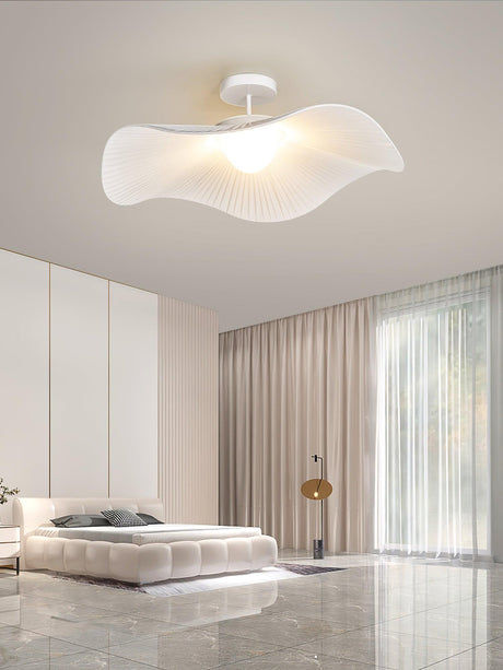 Ceiling light with fabric wings above a round bed, beige curtains and a tiled floor