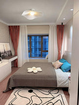 White fabric ceiling fixture in a bedroom with red curtains and a patterned rug