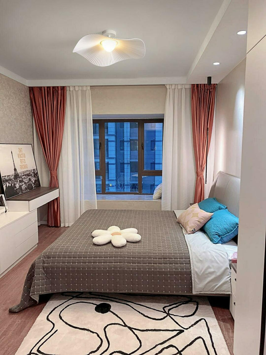White fabric ceiling fixture in a bedroom with red curtains and a patterned rug