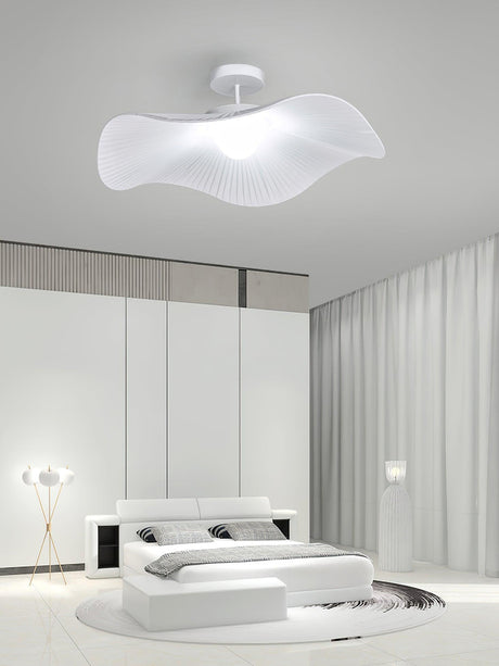 Fabric wing ceiling light in a white bedroom with a low platform bed and a floor lamp