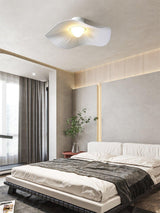 Fabric wing ceiling light above a bed with dark bedding and a wood slat wall