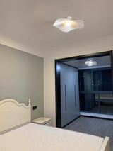 White fabric ceiling fixture in a classic bedroom with a carved bed and a dark doorway
