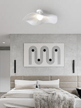 Ceiling light with fabric wings above a bed with a gray headboard and wall art