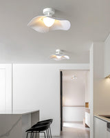 White fabric ceiling fixture lit in an open plan kitchen with black bar stools