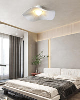 Fabric wing ceiling light in a warm bedroom with a wood slat wall and dark bedding