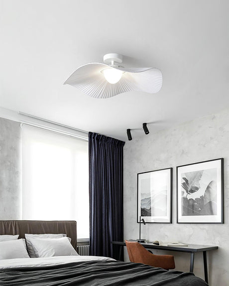 White fabric ceiling fixture above a bed with dark curtains and two framed prints