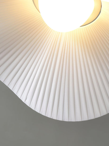 Close view of the lit lamp and the radiating pleats of the fabric shade