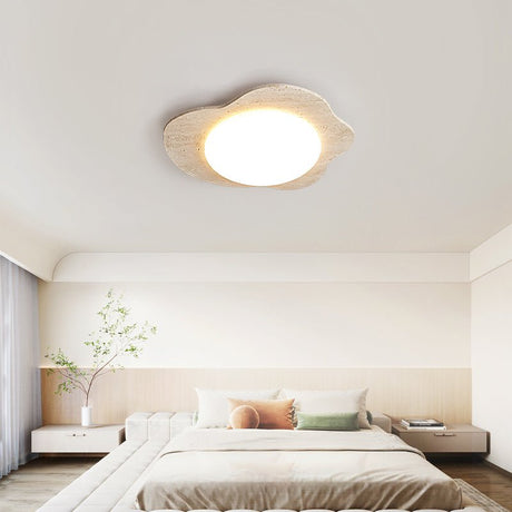 Travertine cloud ceiling light lit above a low platform bed in a pale bedroom