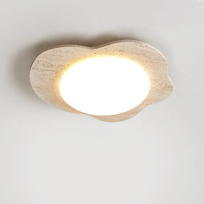 Lit travertine cloud ceiling light shown close up with the porous stone visible
