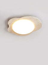 Travertine cloud ceiling light at an angle, the round diffuser glowing at its center