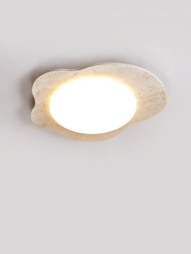 Travertine cloud ceiling light at an angle, the round diffuser glowing at its center