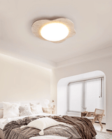 Cloud ceiling light in a bedroom with white bedding, a window seat and a wood chair
