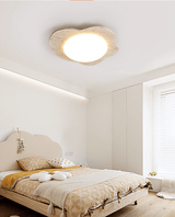 Cloud shaped ceiling fixture above a bed with a rattan headboard and yellow cushions