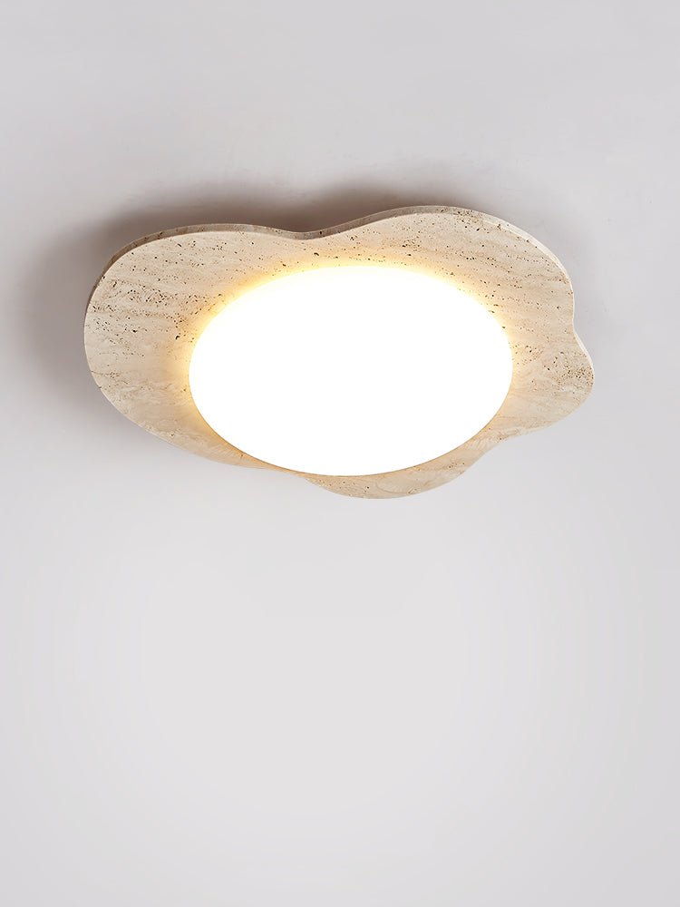 Lit travertine cloud ceiling light from a low angle against a plain wall
