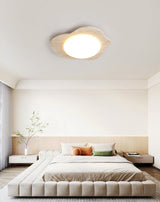 Cloud shaped ceiling light above an upholstered bed in a room with a plant