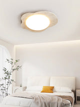Travertine cloud ceiling light lit in a bedroom with white bedding and a side table