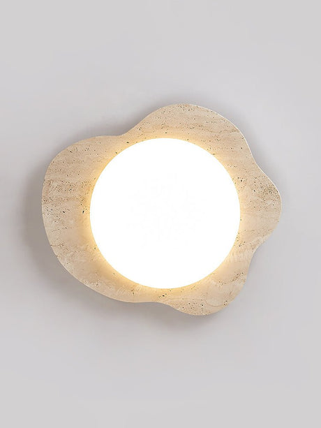 Travertine cloud ceiling light lit flat on, the stone pores visible around the lens