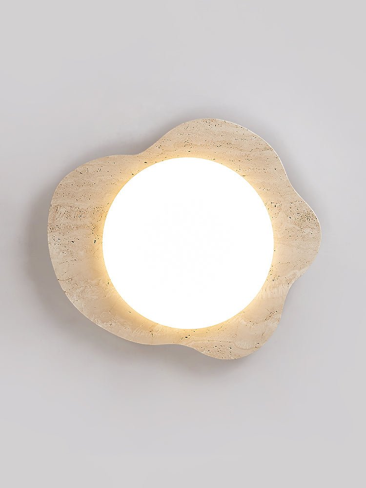 Travertine cloud ceiling light lit flat on, the stone pores visible around the lens