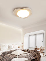 Cloud shaped ceiling fixture above a bed with brown bedding and an arched window