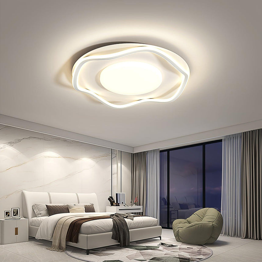Cloud shaped ceiling lamp lit above a bed in a bedroom with a window wall at night