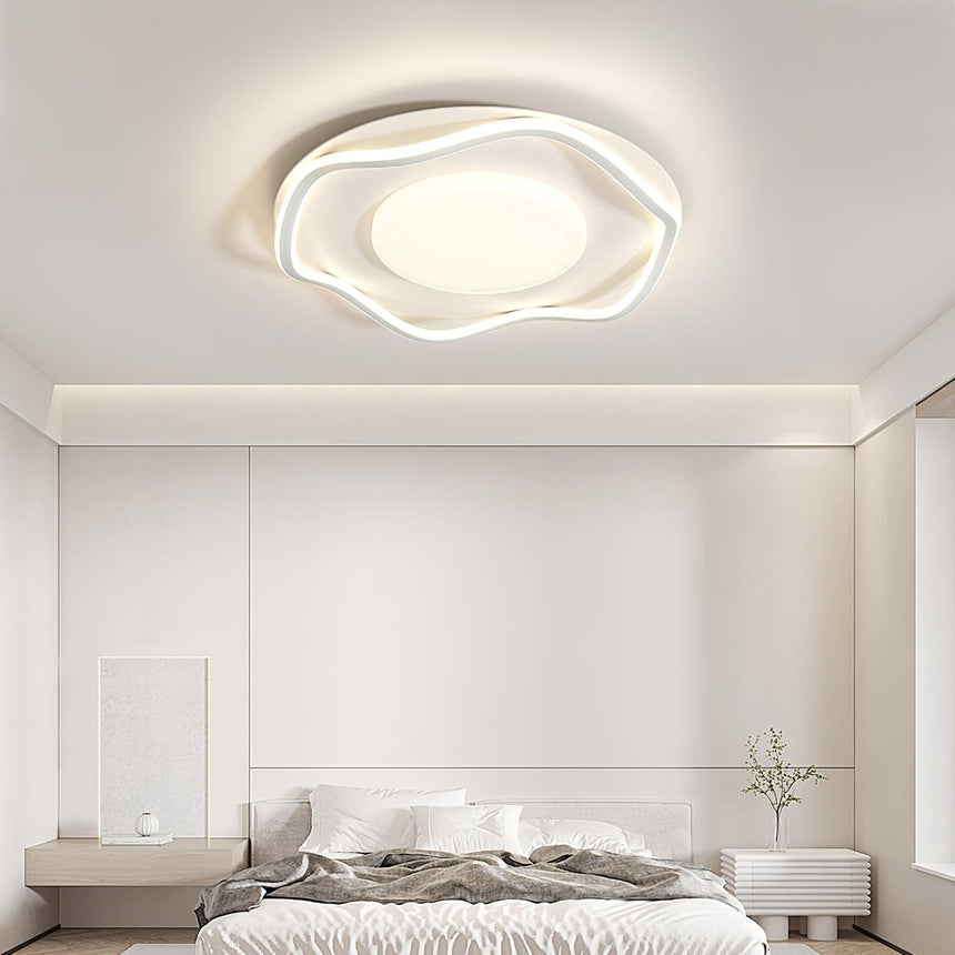 Cloud shaped ceiling lamp lit in a bedroom with a low bed and a framed print
