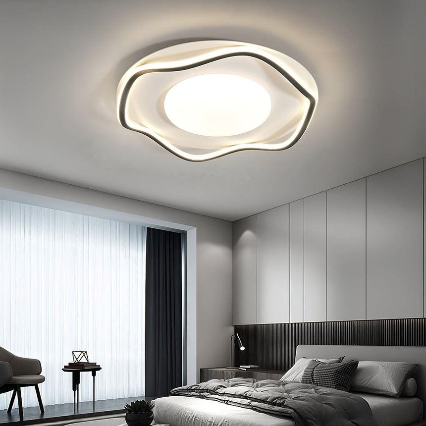 Cloud shaped ceiling lamp lit in a bedroom with dark bedding and a desk by the window